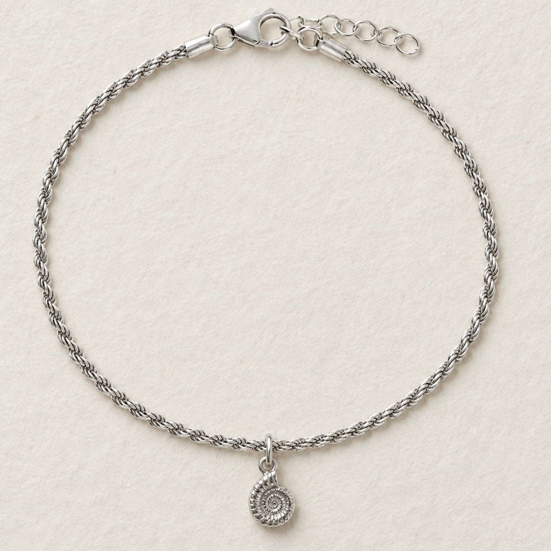sterling silver ammonite fossil rope chain bracelet on cream textured background