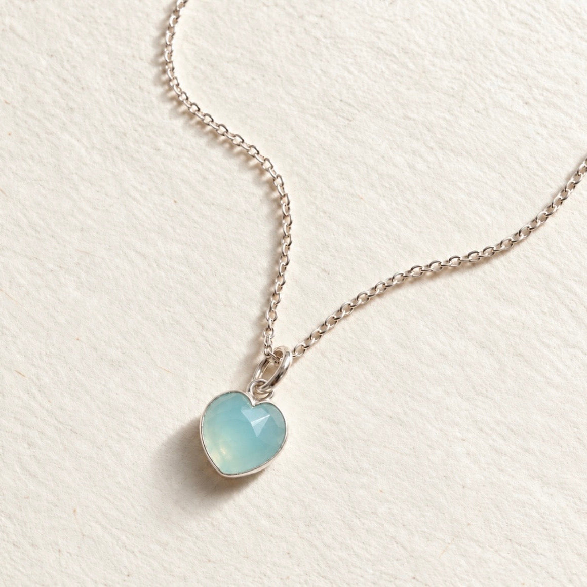 Blue Chalcedony heart gemstone pendant on beige paper background 