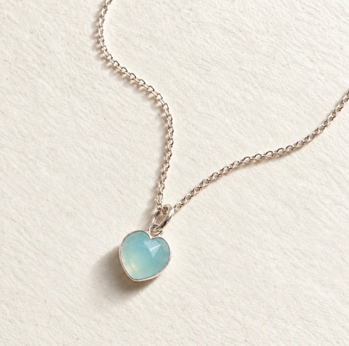 Blue Chalcedony heart gemstone pendant on beige paper background 