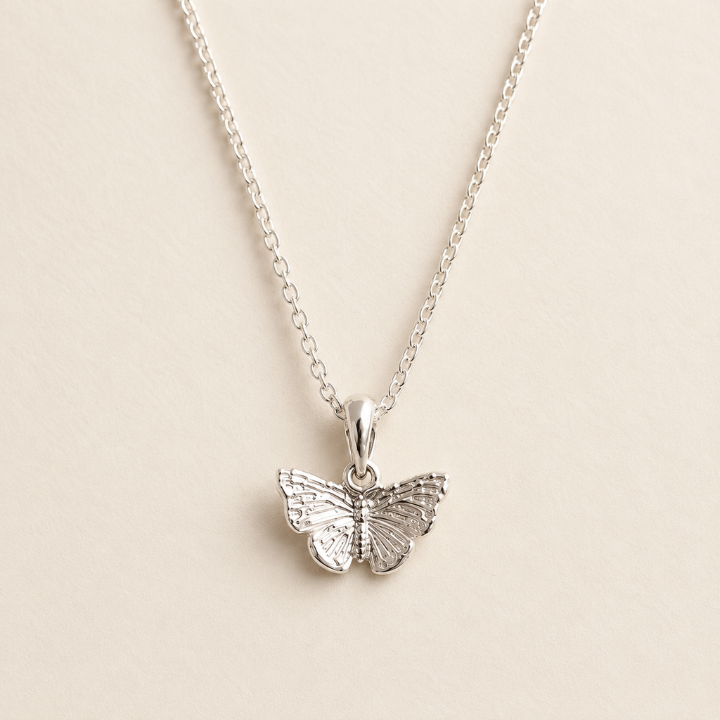 A silver butterfly pendant necklace on a delicate silver chain, displayed against a light beige background.