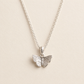 A silver butterfly pendant necklace on a delicate silver chain, displayed against a light beige background.