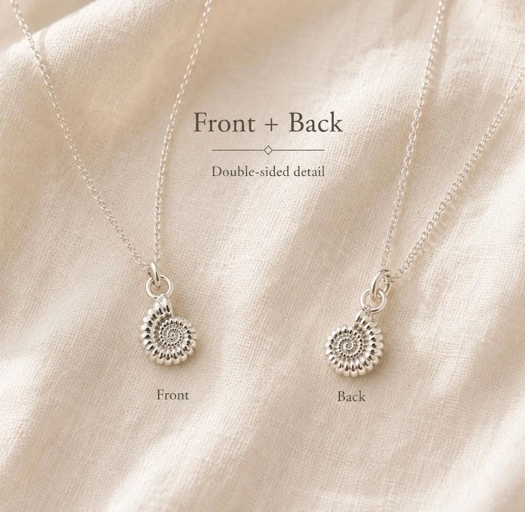 Two views of a silver spiral ammonite pendant necklace on a cream-colored textured fabric background, labelled 'Front + Back' with 'Front' and 'Back' text below each pendant.
