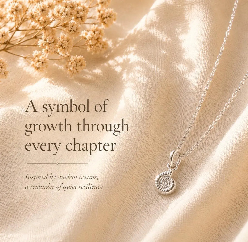 A silver necklace with a textured spiral ammonite pendant is displayed on draped cream-colored fabric with dried flowers in the top left corner and elegant text overlay.