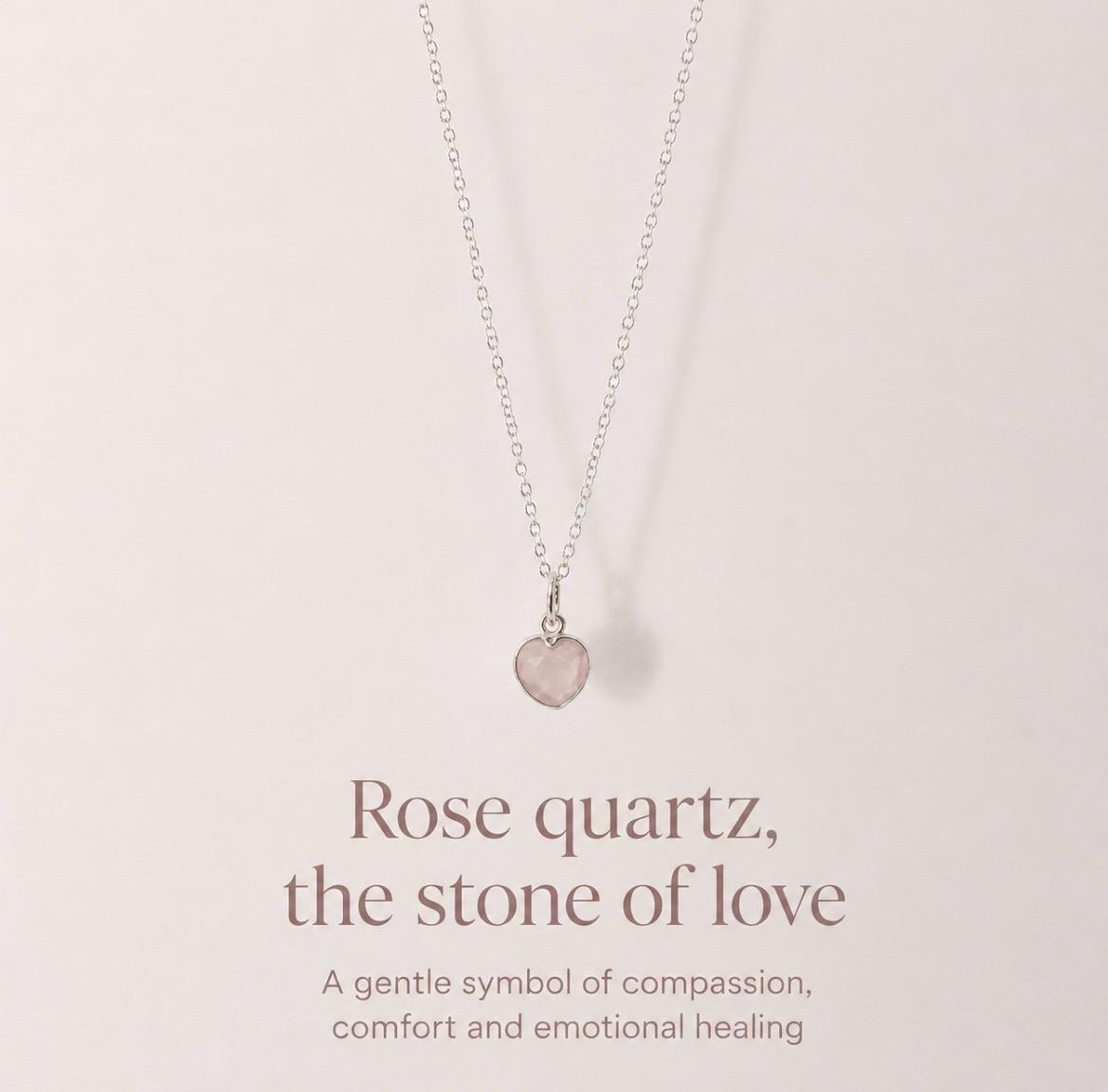 A delicate silver necklace with a small rose quartz heart pendant, displayed against a soft beige background with elegant text below reading 'Rose quartz, the stone of love'.