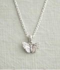A silver butterfly pendant necklace on a delicate silver chain, displayed against a textured light gray fabric background.